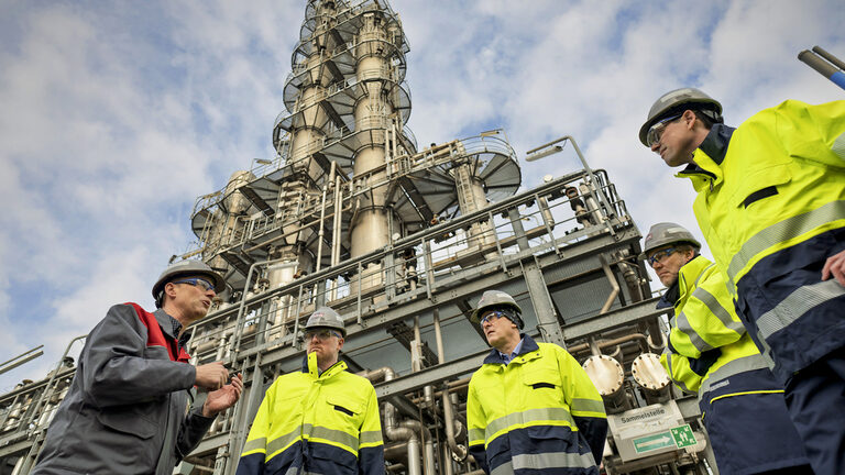 Männer mit Bauhelmen vor maschineller Betriebsanlage