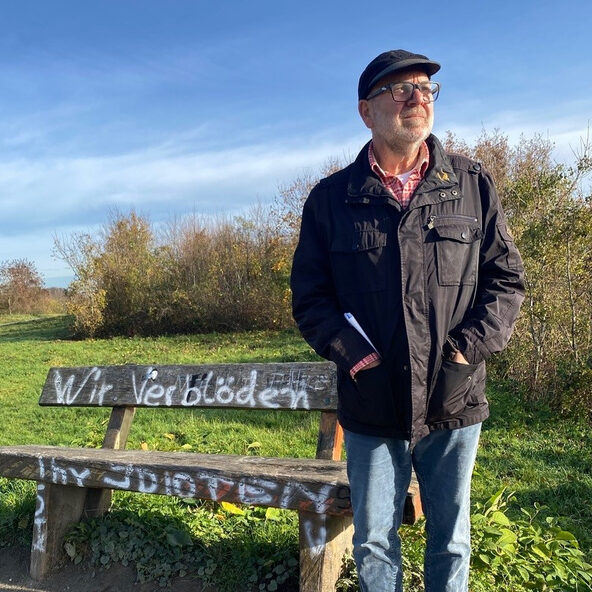 Bernd Beuscher steht vor einer Bank