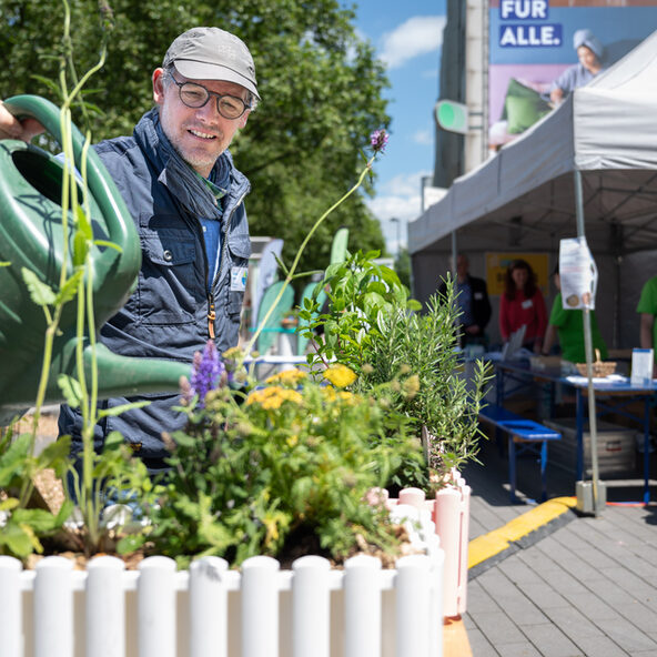 Mann gießt Balkonkasten auf dem Umweltmarkt