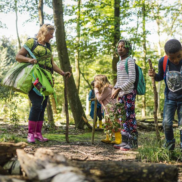 Eine Frau und drei Kinder im Wald.