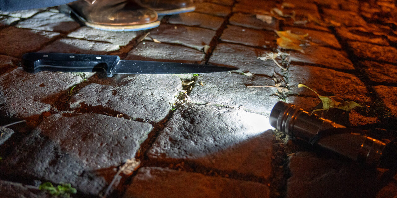 Ein Messer liegt auf einem gepflasterten Platz angestrahlt von einer Taschenlampe.