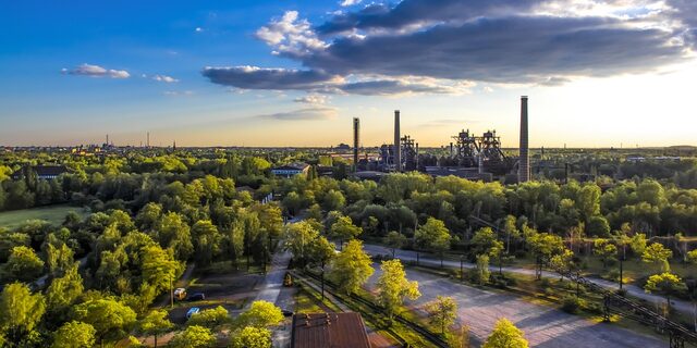 Landschaftspark Duisburg mit Bäumen im Vordergrund und Industrie im Hintergrund