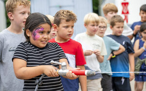 Stadtranderholung Kind hält einen Wasserschlauch