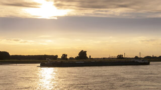 Containerschiff auf dem Rhein bei Sonnenuntergang