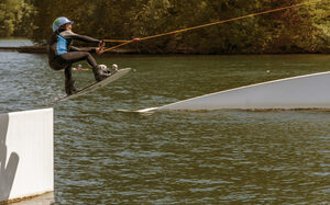 Junge auf Wakeboard fährt über eine Rampe